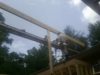 Carpenter setting a ridge beam over a new addition frame — Ice Dam Removal by Roofing Brothers in Saint Thomas