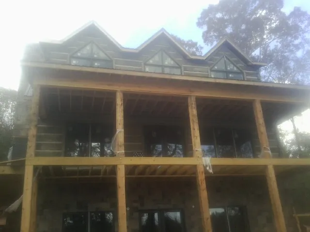 Dormers and porch framing on a large log home under construction — Roof Coating work by our crew in Saint Thomas