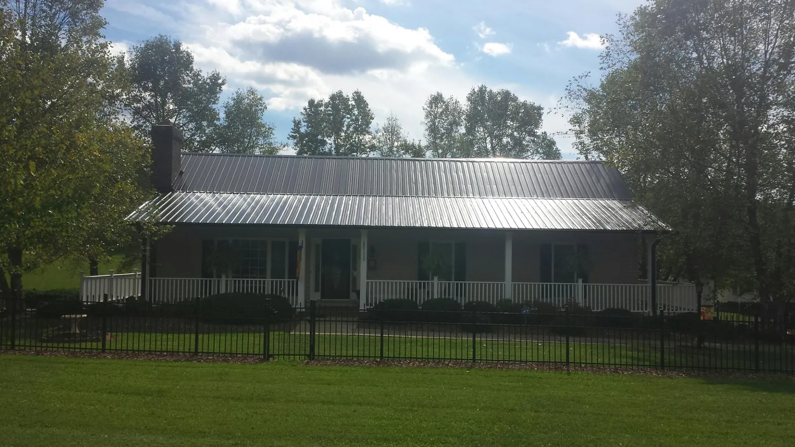 Gray metal roof on a brick ranch with a full width front porch — Gutter Guard Installation work by our crew in Saint Thomas