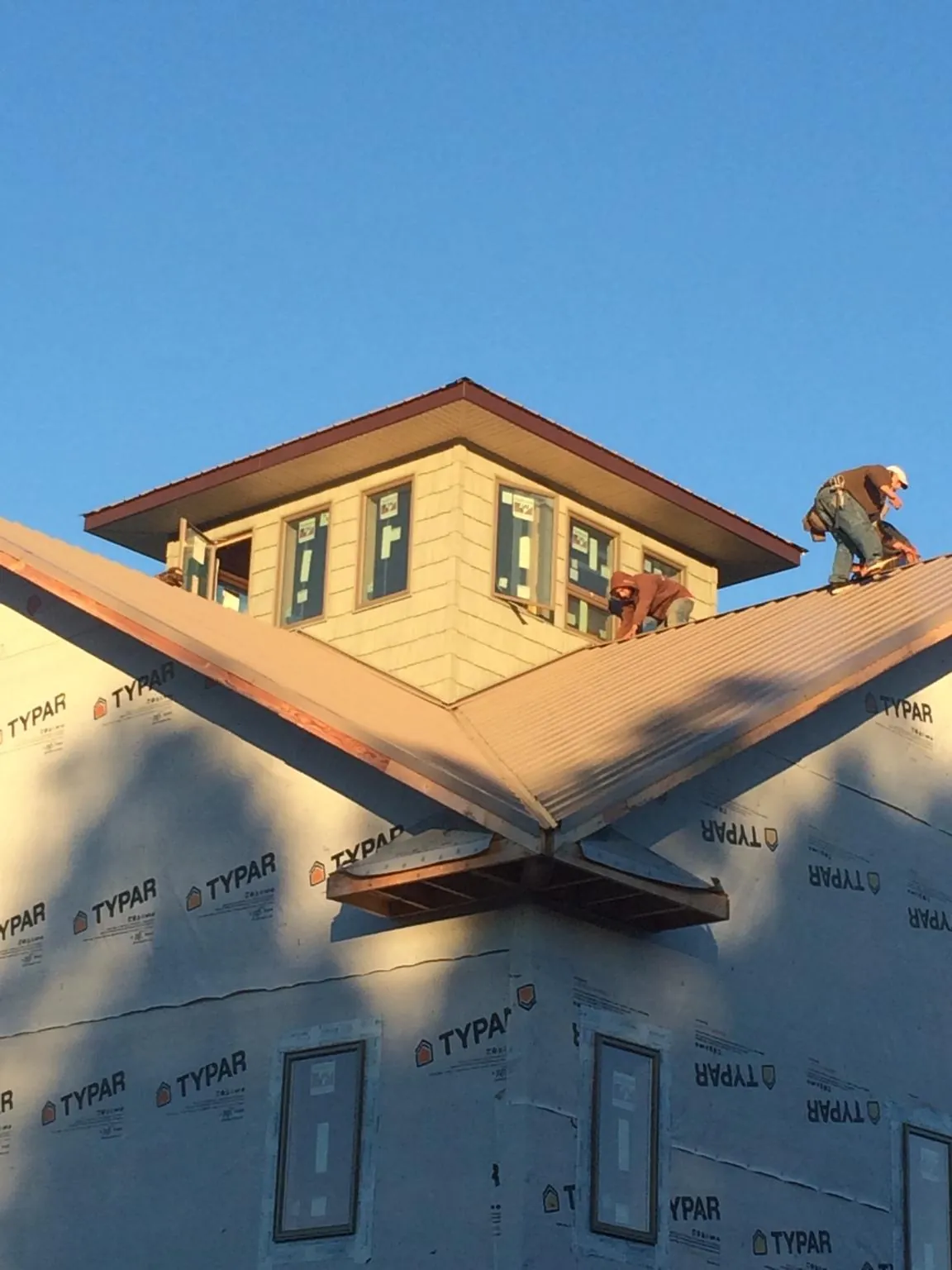 Roofers working around a rooftop cupola on a new metal roof at sunset — Roof Waterproofing in Saint Thomas by Roofing Brothers
